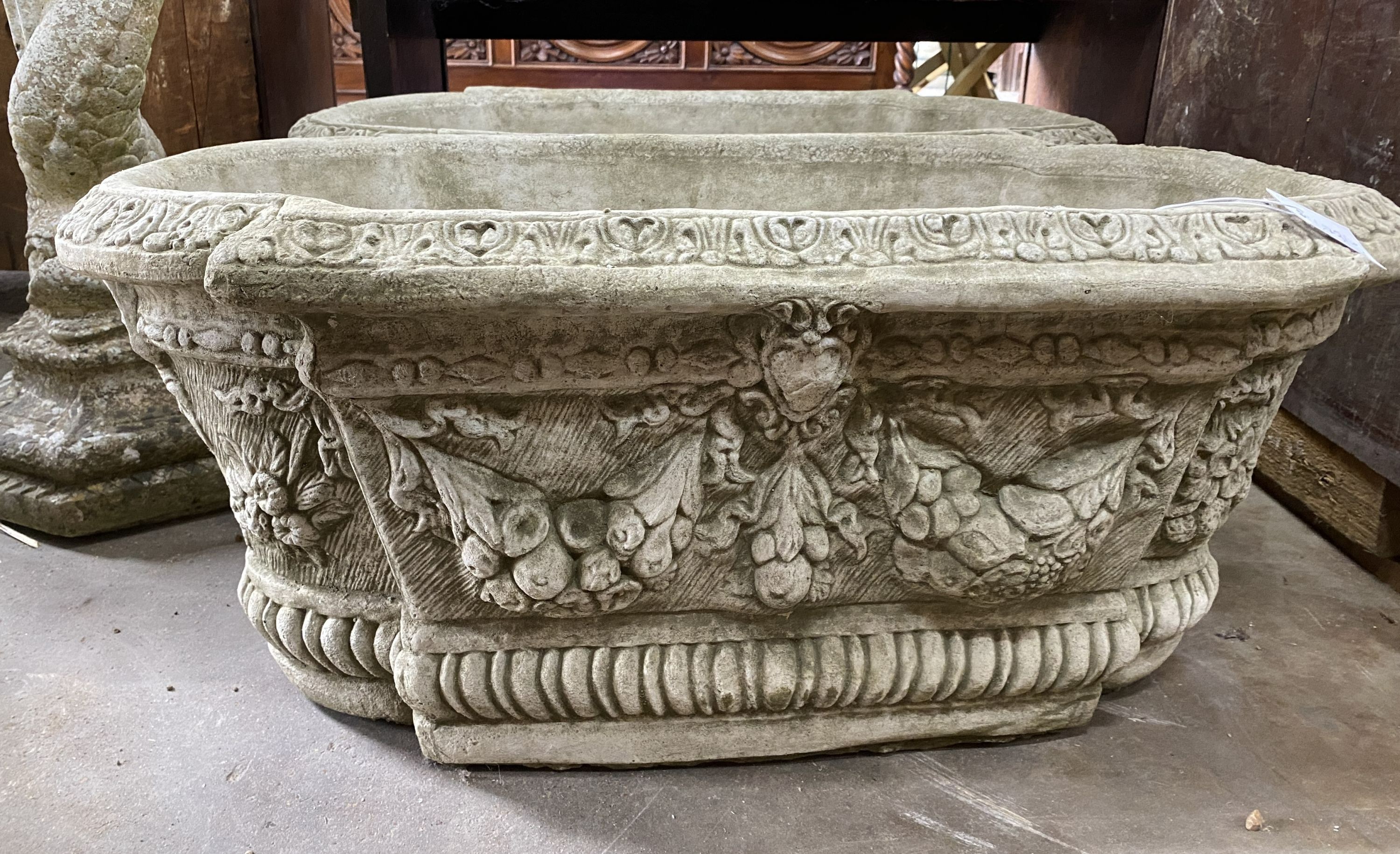 A pair of shaped oval reconstituted stone garden planters with floral swag bodies, width 82cm, depth 42cm, height 34cm